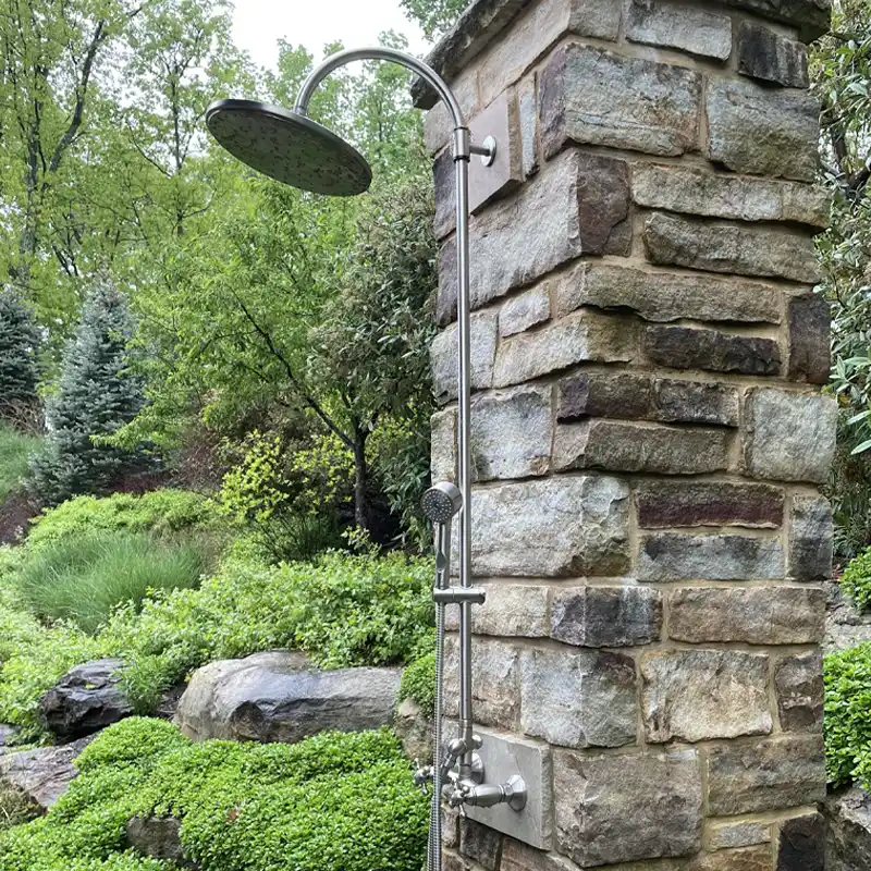 THE Landscape Professionals - Landscape Management Outdoor Plumbing Stone column supporting outdoor shower in foreground; Boulder wall with lush, green ground cover in background